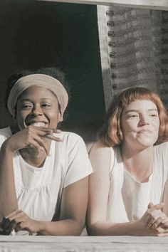 two women sitting next to each other on a window sill with their mouths open