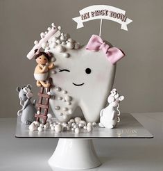 a tooth shaped cake on top of a white plate with a girl and boy figurines