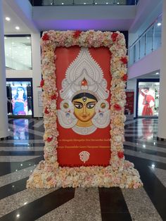 a large red and white sign with flowers on it in a lobby area at an airport