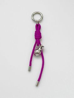 a key chain with a metal hook and purple rope attached to it on a white surface