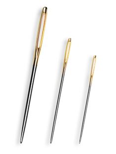 three gold and black pens sitting next to each other on a white surface with one pen in the middle