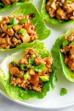 lettuce wraps filled with meat and vegetables on a white plate, ready to be eaten