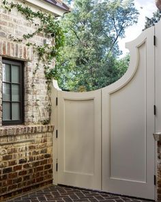 an open white door leading to a brick building with ivy growing on it's side