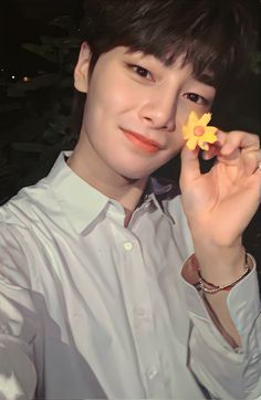 a young man holding a flower in his right hand