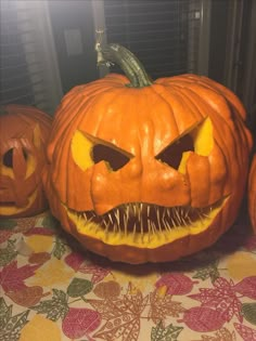 three carved pumpkins sitting on top of a table with their mouths open and teeth missing