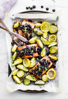 a pan filled with salmon, brussel sprouts and lemon wedges