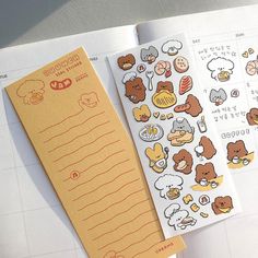 two notebooks with stickers on them sitting next to an open planner book,