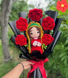 a person holding a bouquet of flowers with a doll in the center and red roses around it