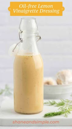 a glass bottle filled with liquid sitting on top of a white table next to a bowl