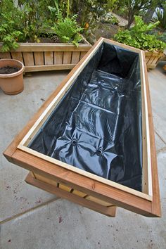 a wooden table with a black tarp over it and some potted plants in the background