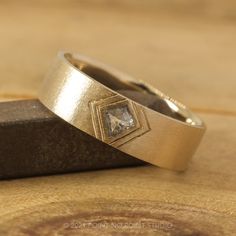 two wedding rings sitting on top of a piece of wood next to a wooden block