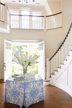 a blue and white table with flowers on it in the middle of a living room