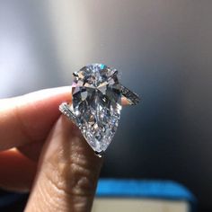 a person holding a diamond in their hand with the ring on it's finger