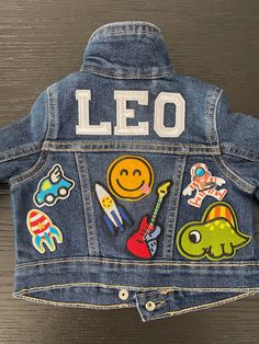 the back of a jean jacket with patches on it that says leo and other stickers