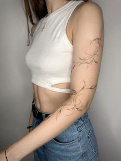 a woman with a tattoo on her arm and shoulder is posing for the camera while wearing jeans