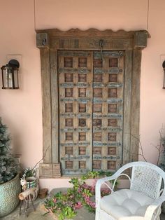 a white chair sitting on top of a patio next to a wooden door and potted plants