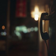 an old fashioned telephone in the dark with street lights and buildings in the back ground