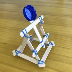 a toy made out of popsicle sticks and plastic cups sitting on top of a wooden table