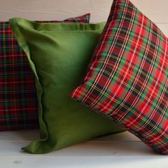 three green and red plaid pillows sitting on top of each other