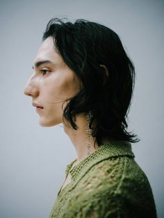 a woman with black hair and earrings on her neck looking off to the side,