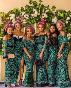 a group of women standing next to each other wearing green dresses and head wraps