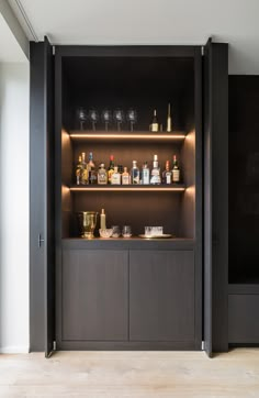 an open cabinet with bottles and glasses on it