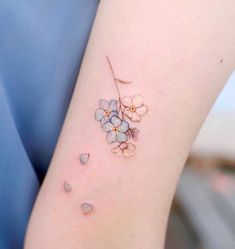 a small flower tattoo on the right arm and shoulder, with tiny blue flowers growing out of it