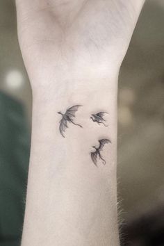 three birds flying in the air on top of a woman's wrist tattoo design