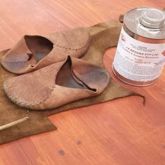 a pair of shoes sitting on top of a wooden floor next to a can of paint