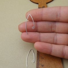 a hand holding a pair of silver earrings