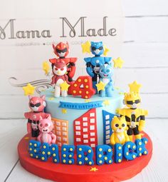 a birthday cake decorated with cartoon characters and stars on it's top, sitting in front of a sign that reads mama made