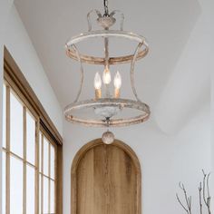 a light fixture hanging from the ceiling in a room with wooden doors and windows,