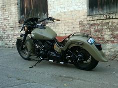 a green motorcycle parked in front of a brick building