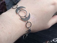 a person wearing a chain bracelet with two crescents on their wrist and one in the middle