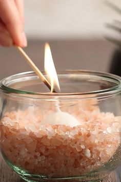 someone lighting a candle in a glass bowl filled with sea salt