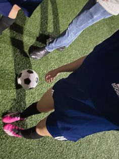 several people are standing on the grass playing with a soccer ball in front of them