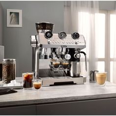 an espresso machine sitting on top of a counter next to two cups of coffee