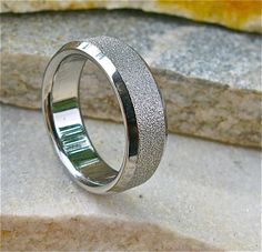 a wedding band with silver glitter inlays sits on top of a stone slab