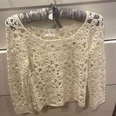 a crochet top hanging on a clothes rack in a store display case, with an empty hanger next to it