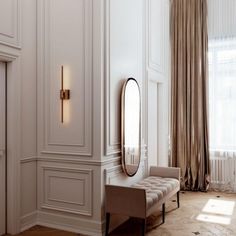 an elegant room with white walls and beige furniture, along with a large mirror on the wall