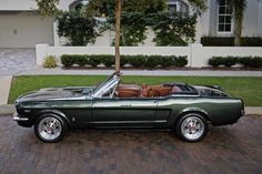 a green mustang convertible parked in front of a house