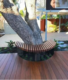 a wooden bench sitting next to a tree on top of a wooden floored area