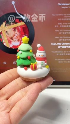 a person is holding a small christmas tree ornament in front of a computer screen