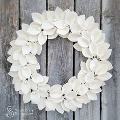 a white wreath is hanging on a wooden fence