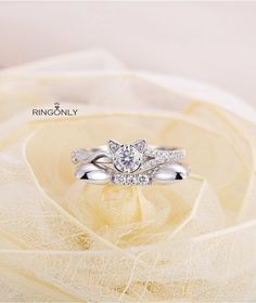 a white gold ring with two diamonds on top of it and a yellow rose in the background