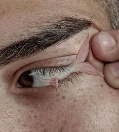 a close up of a persons eye with the tip of his nose sticking out from underneath