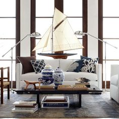 a living room filled with white furniture and tall glass windows covered in lots of natural light