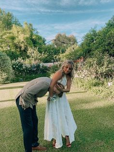 a woman in a white dress and a man in a gray shirt are kissing each other