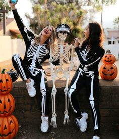 two women in skeleton costumes sitting next to each other with pumpkins and jack - o'- lanterns