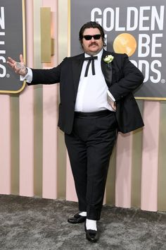 a man in a tuxedo and sunglasses poses for the camera on the red carpet